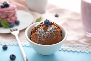 Bowl with tasty blueberry muffin on table
