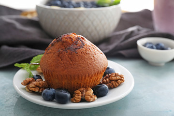 Plate with tasty blueberry muffin on table