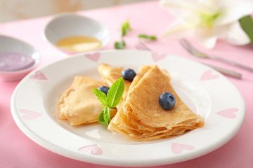 Plate with tasty blini and blueberry on table