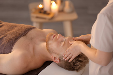 Obraz na płótnie Canvas Handsome young man receiving massage in spa salon