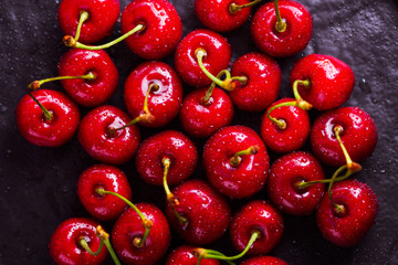 Red cherries on a black background. Sweet cherries in water drops on a dark background. Red berries for vegan. Top view