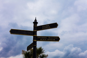 Road sign on the crossroads with blue cloudy sky in the background.