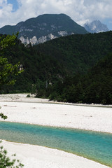 A picturesque panorama in the Dolomites. There are huge mountains covered with snow, coniferous forests, mountain clear azure lake, wild deserted place