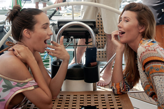 amiche che scherzano su ponte di barca a vela in manovra per navigazione