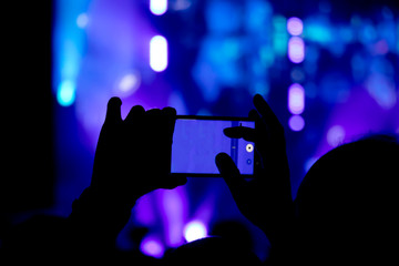  Silhouette of a man hand shooting the concert with his smart phone