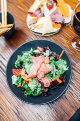 Dinner in the restaurant with Smoked salmon salad and appetizers on wooden dining table. This is Lunch or Dinner Restaurant or Cafe Concept Image.