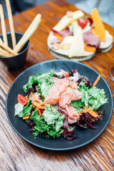 Dinner in the restaurant with Smoked salmon salad and appetizers on wooden dining table. This is Lunch or Dinner Restaurant or Cafe Concept Image.