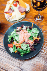 Dinner in the restaurant with Smoked salmon salad and appetizers on wooden dining table. This is Lunch or Dinner Restaurant or Cafe Concept Image.