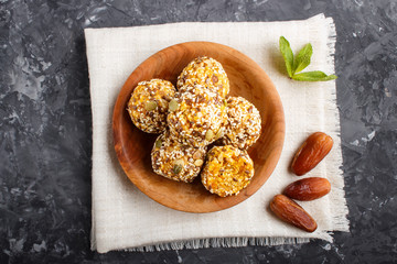 Energy ball cakes with dried apricots, sesame, linen, walnuts and dates on a black concrete  background, top view, close up.