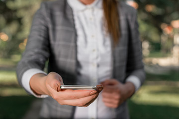 Woman in grey suites holds mobile phone.
