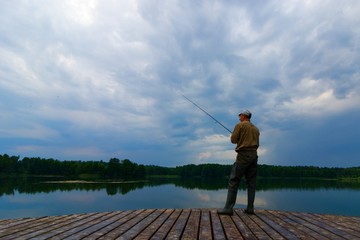 Angler catching the fish from wooden pier 