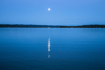 Moon reflecting in calm lake at night 