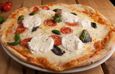 Mozzarella , tomato and arugula pizza on a wooden table.