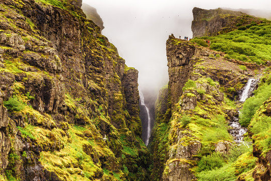 Iceland, Glymur waterfall in Botsna river canyon. Amazing green landscape of Icelandic Canyon. Fantastic misty weather, seagulls soaring over cliffs. Waterfall Glymur is highest in Iceland. - Powered by Adobe