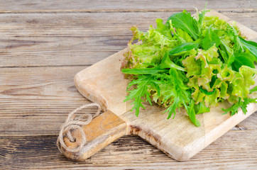 Green mix of different leaves on wooden board, vegetarian food, diet