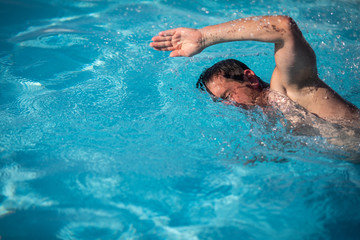 Obraz na płótnie Canvas Male swimmer swimming crawl in an outdoor pool - keeping fit