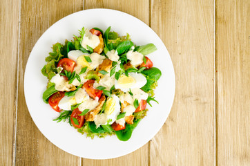 Salad of fresh vegetables, eggs, chicken meat with white sauce.