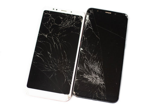 two broken phones of white and black on a white background. cracked touchscreen glass of the touch screen isolate