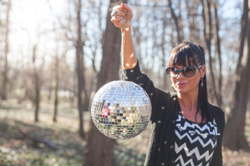 Naklejka premium young woman holding shining disco ball outdoors