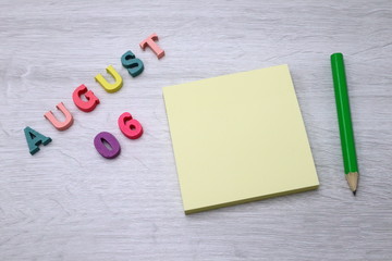 August 6 - Daily colorful Calendar with Block Notes and Pencil on wood table background, empty space for your text or design