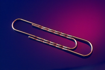 A shot of a single paper clip lying on plexiglass 