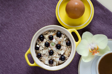 healthy eating concept. breakfast in bed. top view on a tray of oatmeal in a yellow pot, muesli with fresh blueberries, egg, coffee with milk close-up. soft focus