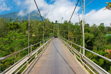 Fototapeta na wymiar Suspension bridge spanning deep gully on the side of active volcano in Java Indonesia.