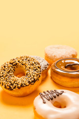A variety of flavoured doughnuts on yellow background portrait orientation food concept image with copy space for text.