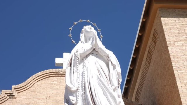 Church and Statue Move Right on Cross on Top. view moves right on the top part of a church with cross with statue in foreground