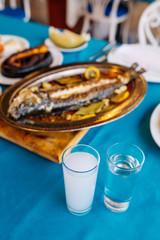 Turkish or Greek restaurant table and food dinner cuisine culture from top view. Traditional Greek ouzo or turkish raki with grilled or fried fish and appetizers on dinner table at restaurant. 