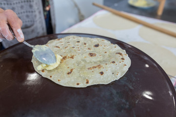 Woman preparing or making borek or bread dough. Hands keep rolling pin on dough with flour. Borek, bread or pastry dough on a wooden table background. Traditional Turkish pide, pita or yufka bread.