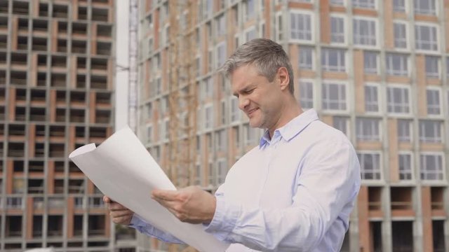 Close up of Construction specialist holding blueprint with using a tablet computer at a construction site 4K