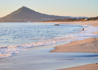 Woman in a white dress on the beach at Moledo, Portugal. With a mountain in background