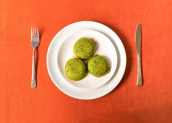 Turkish dessert kadayif with pistacchio on it. Also known antep kadayif in plate on orange background from top view