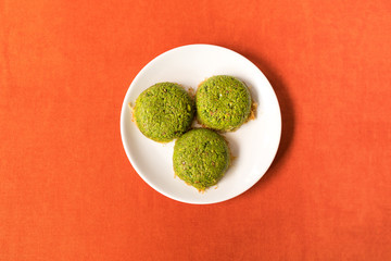 Turkish dessert kadayif with pistacchio on it. Also known antep kadayif in plate on orange background from top view