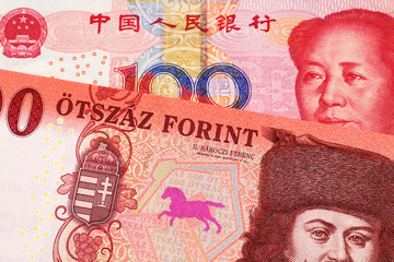 A close up image of a red, one hundred Hungarian forint bill close up with a red, one hundred yuan renminbi Chinese bank note in macro
