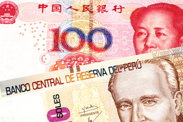 A pastel colored, twenty Peruvian sol bank note, close up in macro with a red, Chinese one hundred yuan bill