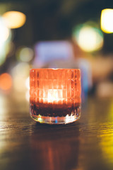 Decorative Orange or red candle light in glass on wooden table at night in cafe or restaurant background interior