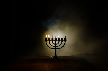 Low key image of jewish holiday Hanukkah background with menorah on dark toned foggy background - obrazy, fototapety, plakaty