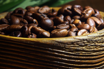 Coffee background, side view close-up, wooden old bowl of roasted coffee beans
