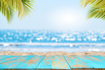 Top of wood table with seascape and palm leaves, blur bokeh light of calm sea and sky at tropical...