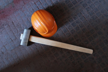 a large working hammer of a sledgehammer and a working helmet on the metal textured floor of the enterprise.