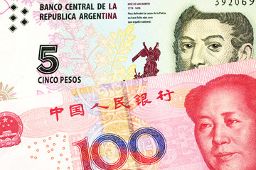 A five peso bill from Argentina, close up in macro with a red, one hundred yuan Chinese renminbi bank note