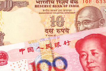 An orange, Indian ten rupee bill, close up with a red, one hundred yuan Chinese renminbi note