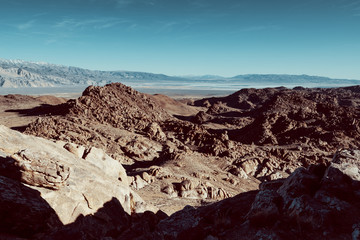 Alabama hills seen from above, with a dirty road. Mountains in the background. blue sky and desert view. 