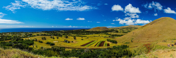 Panoramic view of Easter Island from Puna Pau, where the pukao (moai topknots) were carved, showcasing the island's lush landscape under a sunny sky with scattered clouds