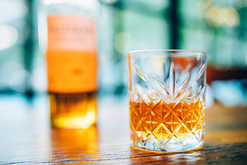 Single glass of whisky or whiskey on wooden table at pub, bar or restaurant at night. Scotch, bourbon or irish whiskey on wooden table. Nightlife concept image