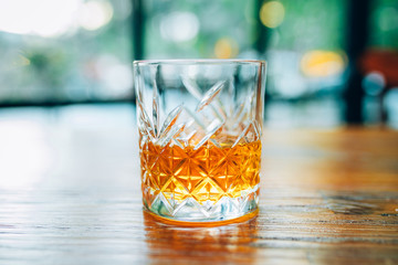 Single glass of whisky or whiskey on wooden table at pub, bar or restaurant at night. Scotch, bourbon or irish whiskey on wooden table. Nightlife concept image