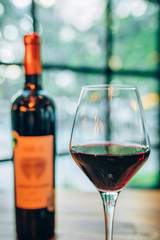 Glass of red wine and bottle of wine on wooden table