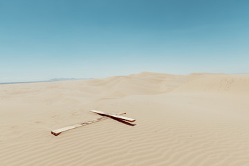 Naklejka premium a wooden cross on a sand dunes with blue sky